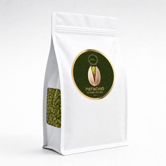 A white stand-up pouch of peeled pistachio kernels, featuring a circular green-and-gold label on the front with a pistachio illustration and a clear window showing green pistachio kernels inside.