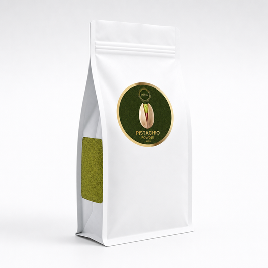 A white stand-up pouch of pistachio powder with a circular green and gold label on the front and a small green window on the side, photographed on a clean white background.