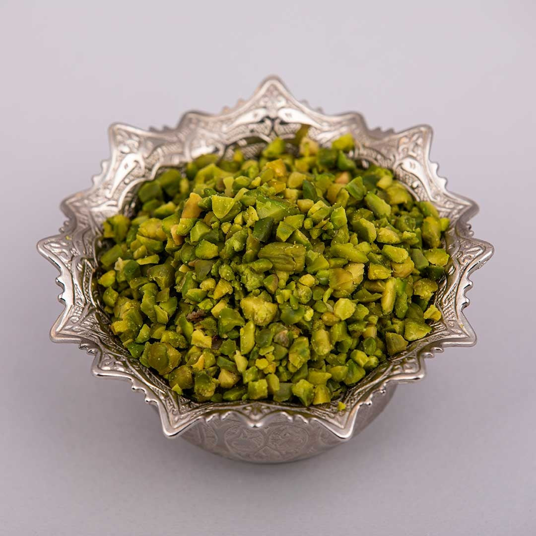 Fresh and premium green pistachio granules on a silver bowl.