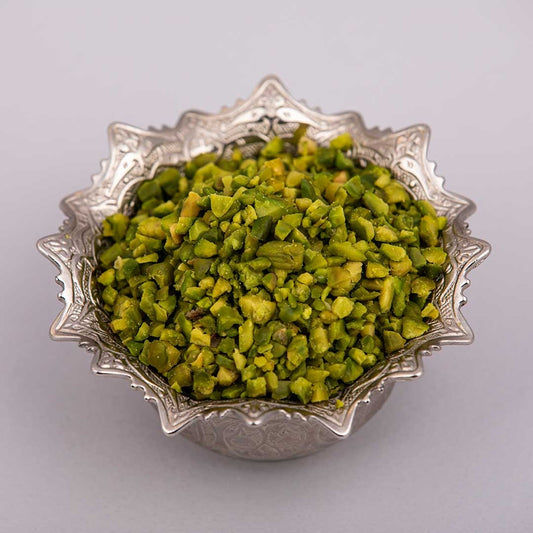 Fresh and premium green pistachio granules on a silver bowl.