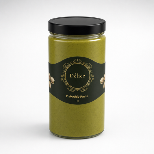 A glass jar of Pistachio Paste by Délice, filled with olive-green paste and topped with a black lid, set against a plain white background.