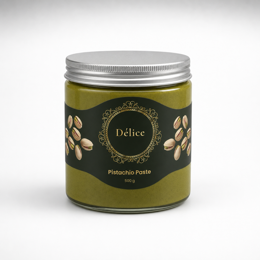 A glass jar of Delice Pistachio Paste with a silver metal lid and a black label decorated with gold details and illustrations of pistachios, set against a clean white background.